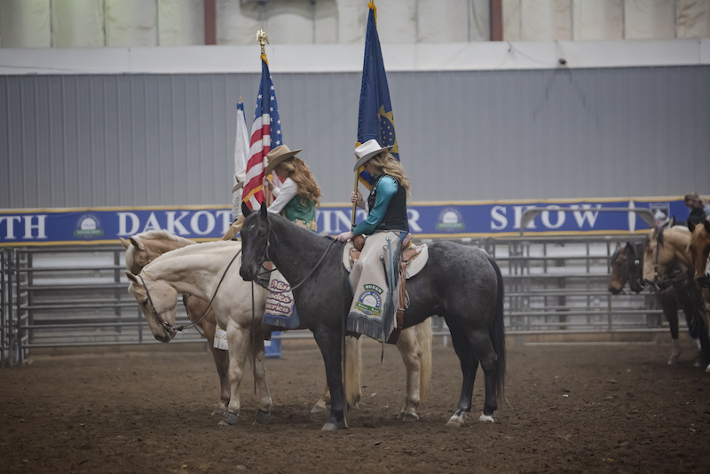Rodeo Queens on their horses holding flags